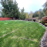 A large yard with grass and trees in the background.